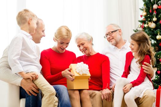 family, holidays, generation, christmas and people concept - smiling family with gift boxes sitting on couch at home