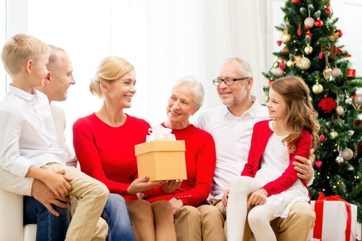 family, holidays, generation, christmas and people concept - smiling family with gift boxes sitting on couch at home