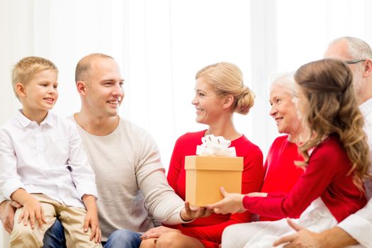 family, holidays, generation, christmas and people concept - smiling family with gift box sitting on couch at home