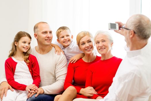 family, holidays, generation, christmas and people concept - smiling family with camera photographing and sitting on couch at home