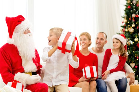 family, holidays, generation, christmas and people concept - smiling family with santa claus and gift boxes at home