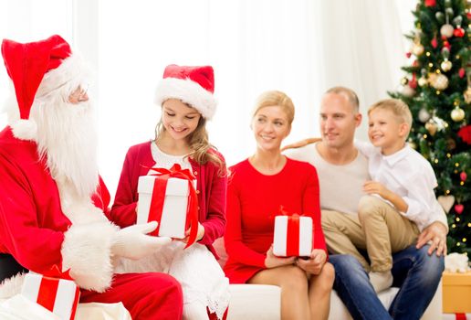 family, holidays, generation, christmas and people concept - smiling family with santa claus and gift boxes at home