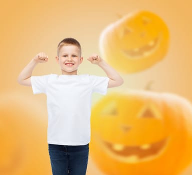 holidays, childhood, happiness, gesture and people concept - smiling little boy in white blank shirt raising hands over halloween pumpkins background