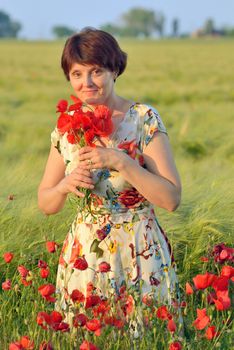woman  in field of poppies in summer sunset