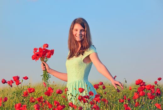 girl  in field of poppies in summer sunset