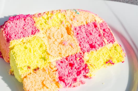 Delicious colorful checkered birthday cake. Cake on white plate.