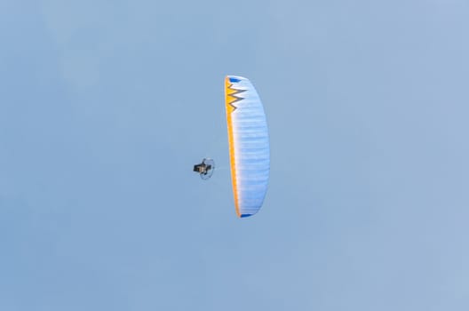 Paramotoring or microlight, paragliding against a blue sky.
