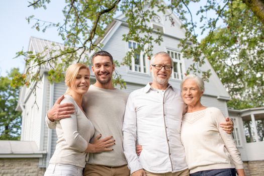 family, happiness, generation, home and people concept - happy family standing in front of house outdoors