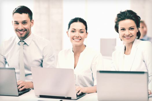 picture of group of people working with laptops in office