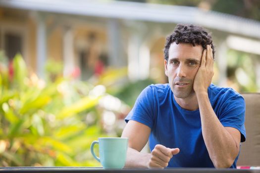 Tired man with hand on head sitting outdoors