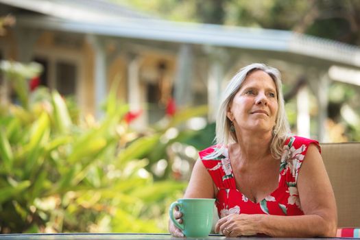 One cheerful mature woman having coffee outdoors