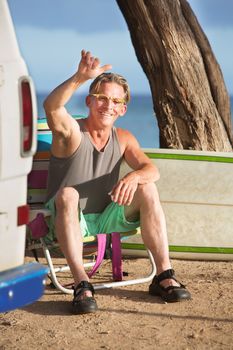 Athletic single male surfer gesturing at ocean beach