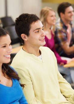 education, high school, teamwork and people concept - group of smiling students sitting in lecture hall