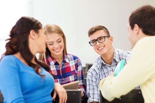 education, high school, teamwork and people concept - group of smiling students sitting and talking in lecture hall