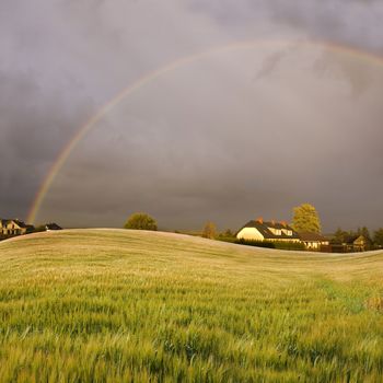Weather conceptual image. Rainbow over the small village.