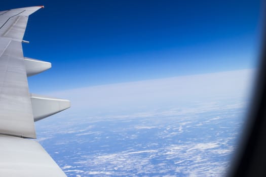 Plane wing against the bright blue sky in flight