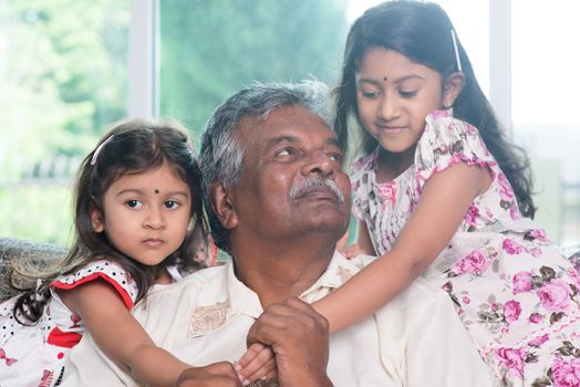 Happy Indian family at home. Asian grandfather and granddaughters playing together. Grandparent and grandchildren indoor lifestyle.