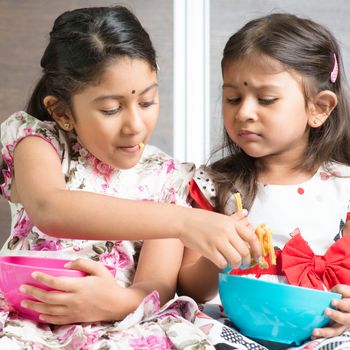 Indian girls sharing food, traditional snack murukku with each other. Asian sibling or children living lifestyle at home.