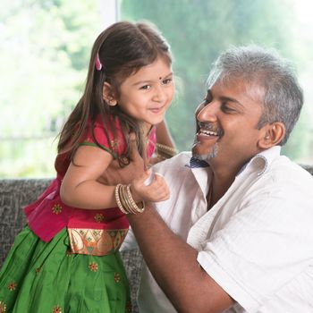 Indian father playing with daughter at home. Asian family indoors living lifestyle.