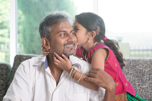 Indian daughter kissing father at home. Asian family indoors living lifestyle.