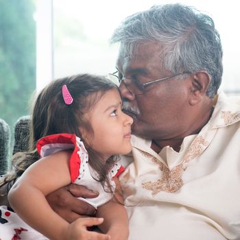 Portrait of Indian family at home. Grandparent kissing grandchild. Grandfather and granddaughter. Asian people living lifestyle.