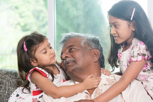 Happy Indian family at home. Asian grandfather and granddaughters having sweet conversation. Grandparent and grandchildren indoor lifestyle.