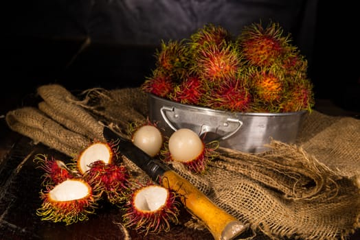 Red rambutan Nephelium lappaceum on broun board. Fruit tropical tree of the family Sapindaceae , native to South - East Asia , cultivated in many countries in the region