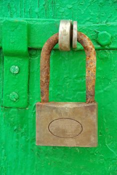 Ancient and rusty iron padlock on a wooden green door