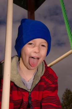 Boy playing in a playground with tonbue poking out.