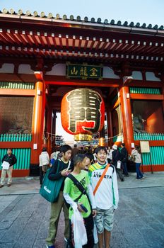 Tokyo, Japan - November 21, 2013: Tourists at the entrance of Sensoji temple. The temple is approached via the Nakamise, shopping street, providing tourist souvenirs.