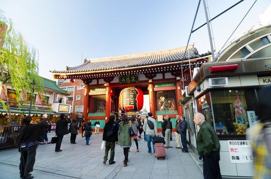 Tokyo, Japan - November 21, 2013: Tourists at the entrance of Sensoji temple. The temple is approached via the Nakamise, shopping street, providing tourist souvenirs.
