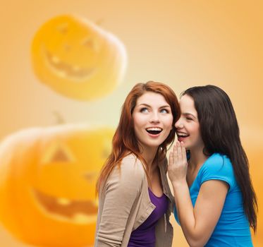 happiness, holidays, firendship and people concept - smiling teenage girls gossiping over halloween pumpkins background