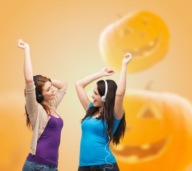 happiness, holidays, friendship and people concept - smiling teenage girls hugging over halloween pumpkins background