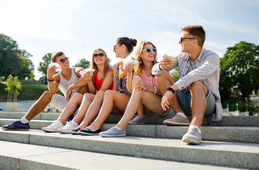 friendship, leisure, summer and people concept - group of smiling friends in sunglasses sitting with food on city square