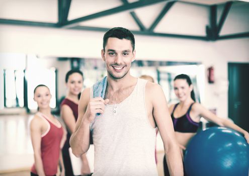 fitness, sport, training, gym and lifestyle concept - smiling man standing in front of the group of people in gym