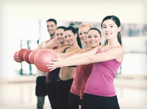 fitness, sport, training, gym and lifestyle concept - group of smiling people working out with stability balls in the gym