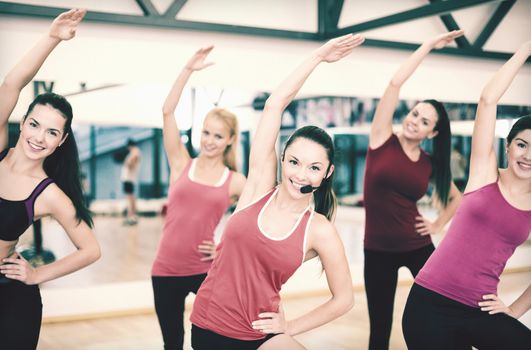 fitness, sport, training, gym and lifestyle concept - group of smiling people stretching in the gym