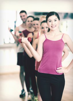 fitness, sport, training, gym and lifestyle concept - group of smiling people lifting dumbbells in the gym