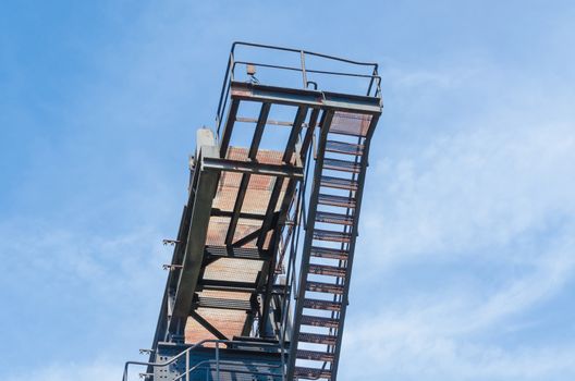 Detail view of a factory tower against a blue sky