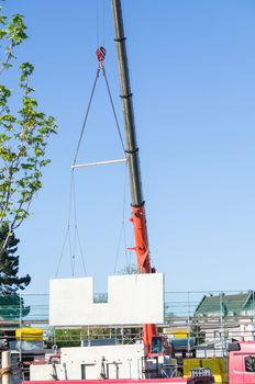 Mobile Crane car on a construction site. Lifts up a concrete wall.