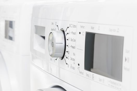 closeup of new white laundry or washing machine, selective focus on control elements