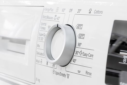 closeup of new white laundry or washing machine, selective focus on control elements