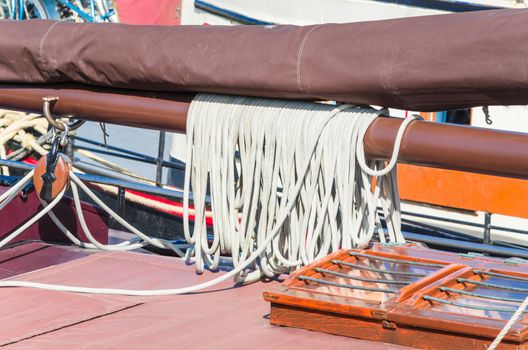 Close up of a ship's rail of an old wooden sailing boat. rope to a sailing mast.