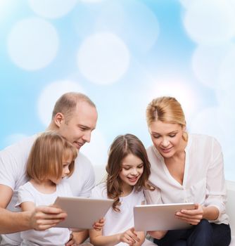 family, holidays, technology and people - smiling mother, father and little girls with tablet pc computers over blue lights background