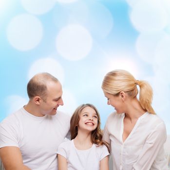 family, childhood, holidays and people - smiling mother, father and little girl over blue lights background