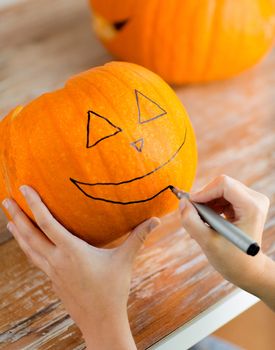 holidays, halloween, decoration and people concept - close up of woman with pumpkins at home