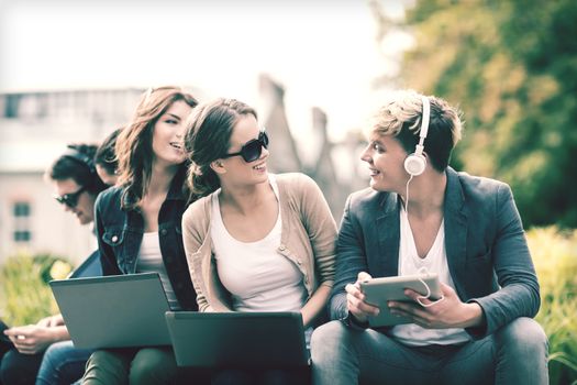 summer, internet, education, campus and teenage concept - group of students or teenagers with laptop and tablet computers hanging out