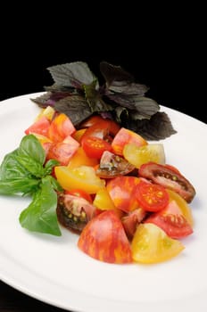 slices of different varieties of tomato with basil on a plate