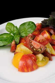 slices of different varieties of tomato with basil on a plate