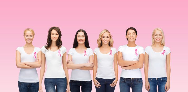 healthcare, people and medicine concept - group of smiling women in blank t-shirts with breast cancer awareness ribbons over pink background